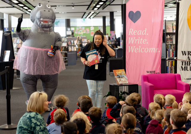 Image of Festival Director Aimee Chan and a hippo in front of an audience of school children