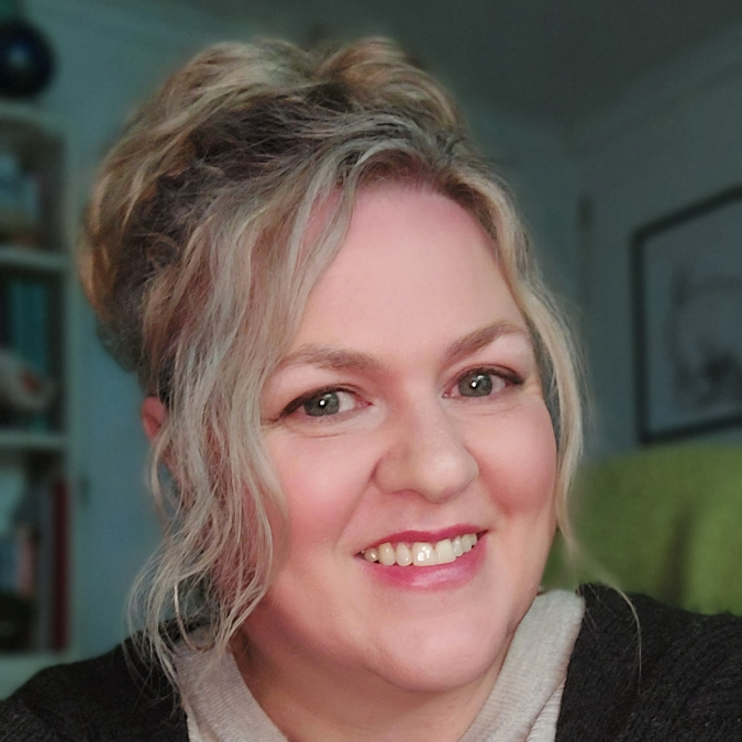 Headshot of author Tania Ingram with blonde hair in an updo, smiling warmly in a grey cardigan with a bookshelf in the background.